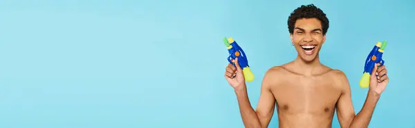 Jolly bello afroamericano uomo in posa con due pistole ad acqua e sorridente alla macchina fotografica felicemente, banner — Foto stock