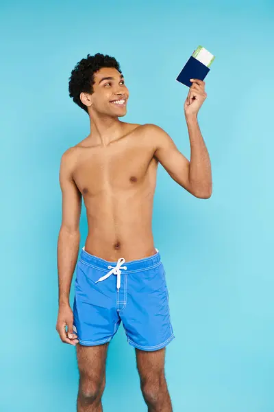 Attractive joyous african american man looking at his passport and ticket on blue background — Stock Photo