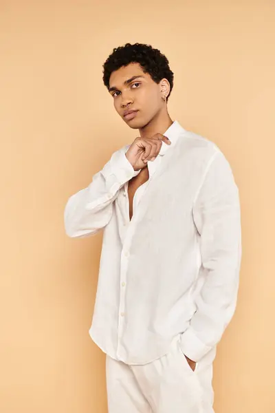 Schöner junger afrikanisch-amerikanischer Mann in weißer Kleidung posiert vor beigem Hintergrund und schaut in die Kamera — Stockfoto