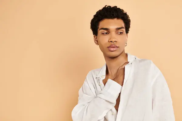 Raffinato chic uomo africano americano in elegante abbigliamento bianco guardando lontano su sfondo beige — Foto stock
