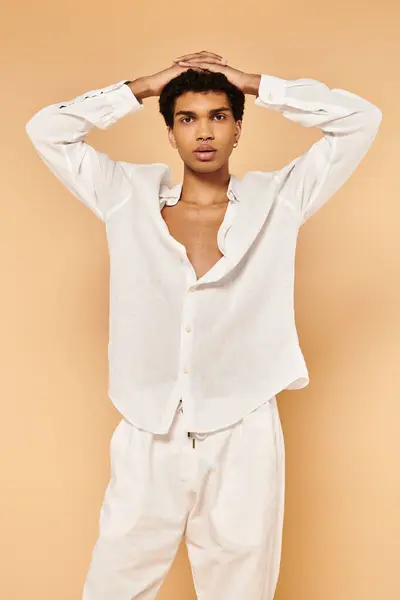 Élégant homme afro-américain en tenue blanche posant sur fond beige et regardant la caméra — Photo de stock