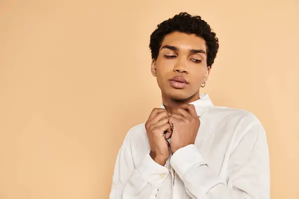Attrayant chic homme afro-américain dans des vêtements blancs élégants regardant loin sur fond beige — Photo de stock