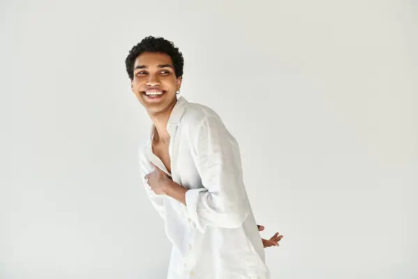 Modelo masculino afroamericano seductor feliz en traje de lino blanco mirando hacia otro lado en fondo beige - foto de stock