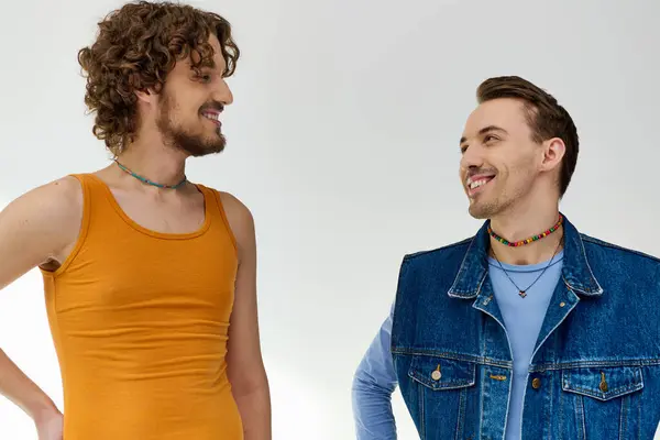 Appealing happy lgbt friends in vivid attires looking at each other on gray backdrop, pride month — Stock Photo