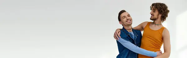 Boa aparência alegre lgbtq amigos em roupas vibrantes abraçando no fundo cinza, mês de orgulho, banner — Fotografia de Stock