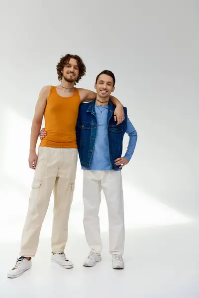 Joyful good looking lgbtq friends in stylish outfits posing on gray backdrop and looking at camera — Stock Photo