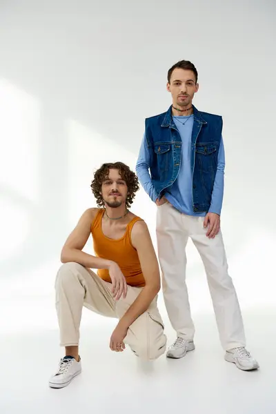 Trendy cheerful lgbtq friends in stylish outfits posing on gray backdrop and looking at camera — Stock Photo