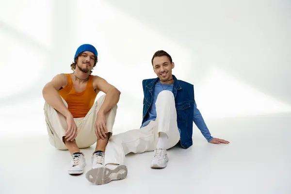 Apelando alegres amigos lgbtq em roupas elegantes posando em pano de fundo cinza e olhando para a câmera — Stock Photo