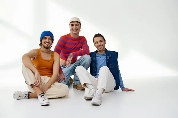 Радісні друзі lgbtq у яскравому вбранні позують разом на сірому фоні і посміхаються на камеру — стокове фото