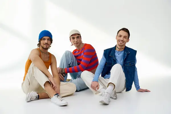 Joyous lgbtq friends in vibrant attires posing together on gray backdrop and smiling at camera — Stock Photo