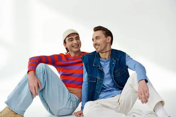 Двое веселых молодых друзей lgbtq в яркой стильной одежде позируют вместе на сером фоне — стоковое фото