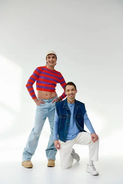 Due amici lgbt gioiosi di bell'aspetto in abiti vibranti guardando la fotocamera in posa su sfondo grigio — Foto stock