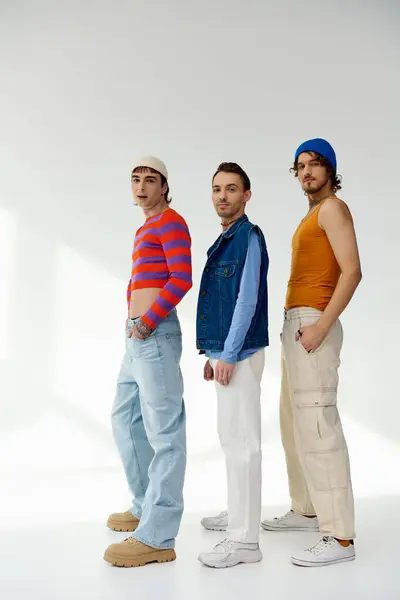 Appealing jolly lgbt friends in vivid attires posing actively on gray backdrop and looking at camera — Stock Photo