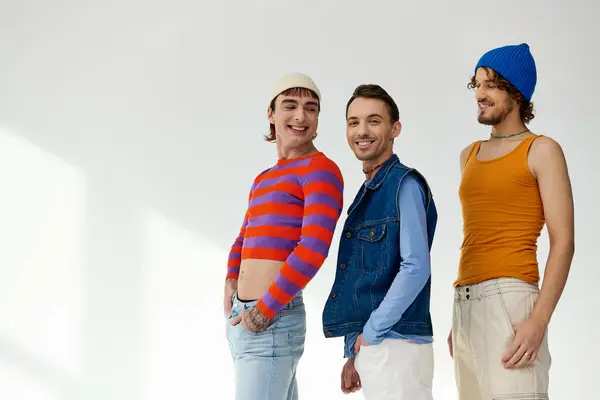 Joyful good looking lgbtq male friends in casual vibrant outfits posing actively on gray backdrop — Stock Photo
