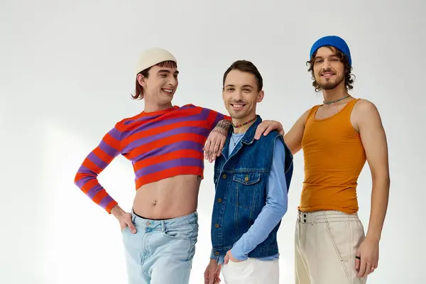 Joyous good looking lgbtq male friends in casual vibrant outfits posing actively on gray backdrop — Stock Photo