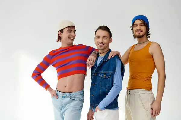 Alegre bien parecido lgbtq amigos masculinos en casual vibrante trajes posando activamente sobre gris telón de fondo — Stock Photo