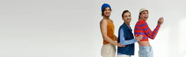 Merry lgbtq friends in vivid attires posing actively on gray backdrop and looking at camera, banner — Stock Photo