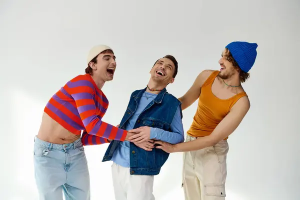 Alegre boa aparência lgbtq amigos masculinos em roupas vibrantes casuais posando ativamente no fundo cinza — Fotografia de Stock