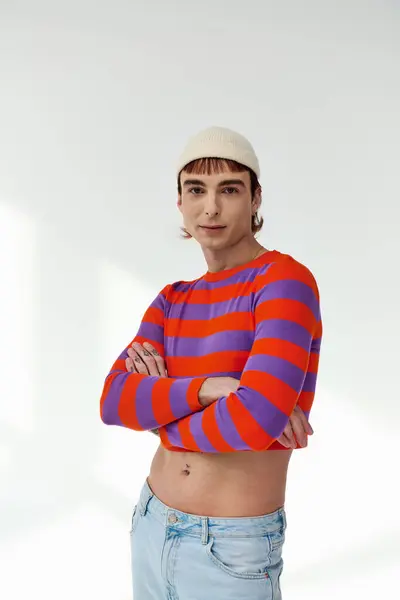Alegre de moda gay hombre con blanco sombrero en vívido atuendo posando en gris telón de fondo y mirando a la cámara - foto de stock