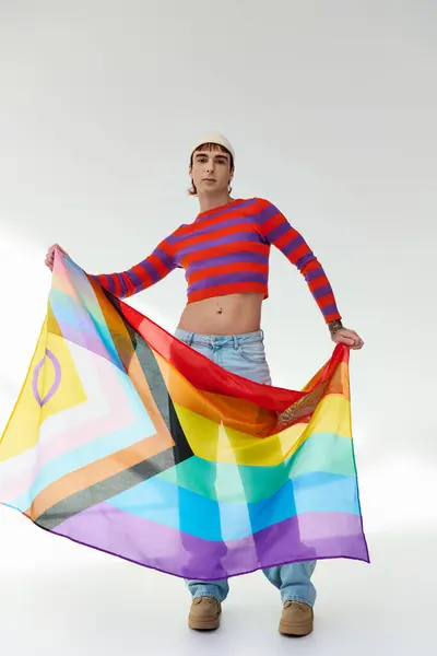 Alegre atractivo gay hombre en vívido traje con blanco sombrero sosteniendo arco iris bandera y mirando a cámara - foto de stock