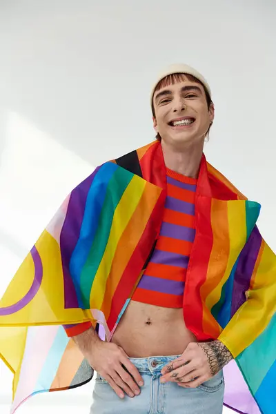 Bonito alegre gay homem no vívido roupa com branco chapéu segurando arco-íris bandeira e olhando para câmera — Stock Photo