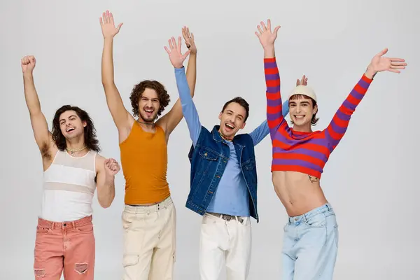 Four contented attractive gay men in vivid attires smiling at camera while posing on gray backdrop — Stock Photo