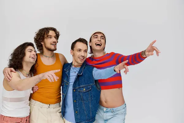 Appealing joyous lgbtq men in vibrant attires posing together on gray backdrop and looking away — Stock Photo