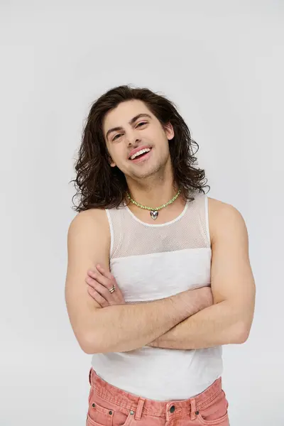 Весёлый привлекательный гей с длинными волосами в повседневной одежде, улыбающийся в камеру на сером фоне — стоковое фото