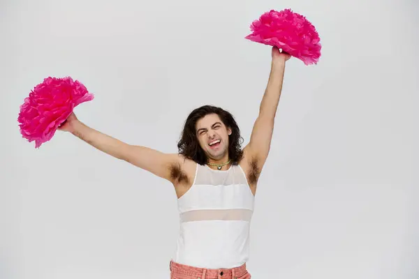 Cheerful attractive gay man in vibrant attire posing happily with pom poms and smiling at camera — Stock Photo
