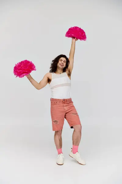 Joyous attractive gay man in vibrant attire posing happily with pom poms and smiling at camera — Stock Photo