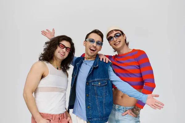 Tres voguish atractivos amigos gay en vibrantes trajes de moda con gafas de sol chic, mes orgullo - foto de stock