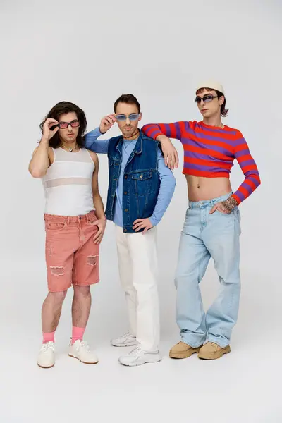 Three stylish appealing gay friends in vibrant trendy attires with chic sunglasses, pride month — Stock Photo