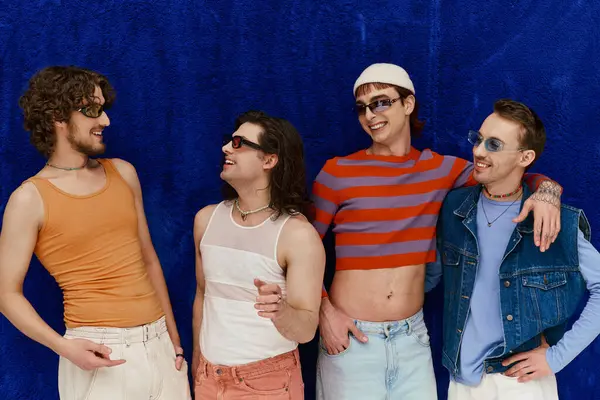 Elegante alegre atraente gay homens com óculos de sol no vívido trajes posando no azul pano de fundo, orgulho — Fotografia de Stock