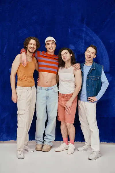 Четыре веселых привлекательных стильных друзей-геев в повседневных ярких одеждах на голубом фоне, месяц гордости — стоковое фото