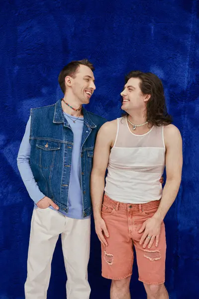Positivo atractivo elegante gay amigos en acogedor trajes en azul oscuro telón de fondo, orgullo mes - foto de stock