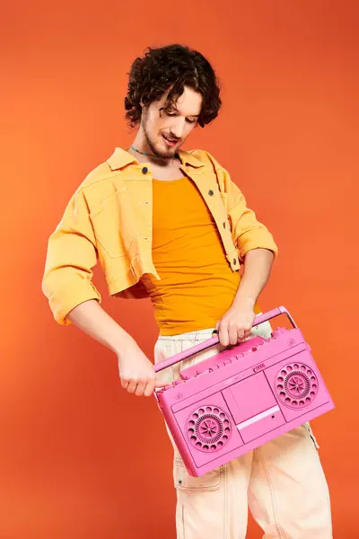 Good looking joyous gay man posing cheerfully with tape recorder on orange backdrop, pride month — Stock Photo