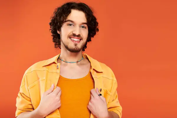 Allegro attraente gay uomo con scuro capelli e vibrante trucco posa su arancio sfondo orgoglio mese — Foto stock