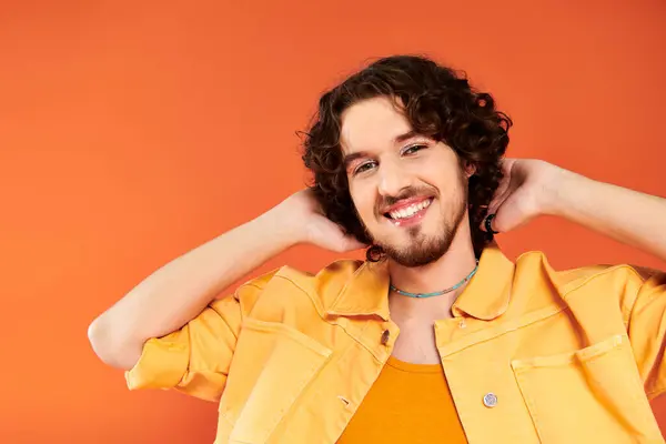 Gioioso attraente gay uomo con scuro capelli e vibrante trucco posa su arancio sfondo orgoglio mese — Foto stock