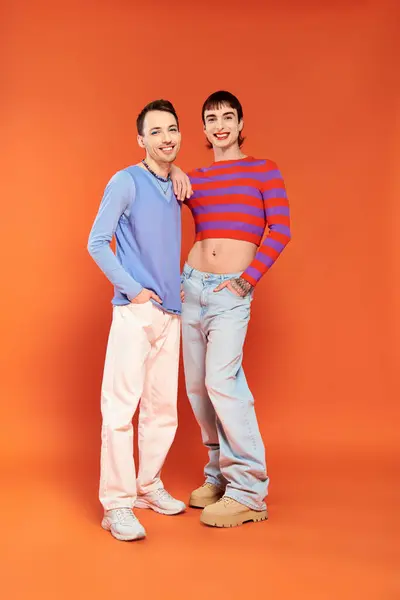Два веселых молодых гея с ярким макияжем в стильных нарядах позируют и улыбаются в камеру — стоковое фото