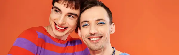 Jolly gay friends with vivid makeup posing together on orange backdrop, pride month, banner — Stock Photo