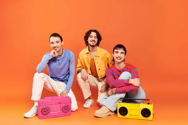 Tre allegri amici gay attraenti in abiti vivaci in posa con registratori a nastro, mese di orgoglio — Foto stock