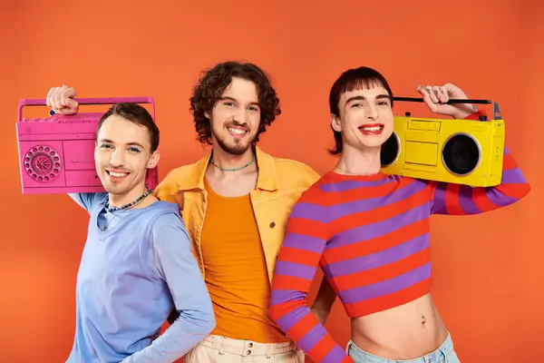 Tre gioiosi attraente gay amici in vivido abbigliamento posa con nastro registratori, orgoglio mese — Foto stock