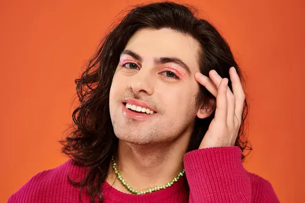 Довольный симпатичный гей с длинными волосами в пурпурной толстовке, смотрящий в камеру, месяц гордости — стоковое фото