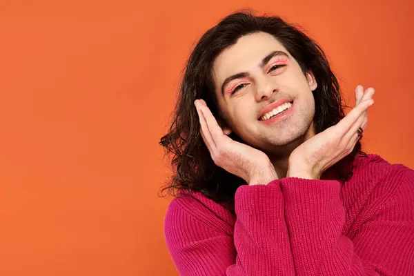 Радостный красивый гей мужчина с длинными волосами в пурпурной толстовке, смотрящий в камеру, месяц гордости — стоковое фото