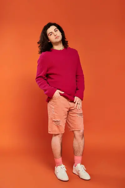 Stylish good looking gay man with long hair in magenta sweatshirt looking at camera, pride month — Stock Photo