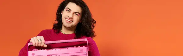 Happy gay man in magenta sweatshirt with long hair holding tape recorder smiling at camera, banner — Stock Photo