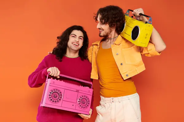 Zwei fröhlich attraktive schwule Freunde in lebendigen Kleidern posieren mit Tonbandgeräten, stolzer Monat — Stockfoto