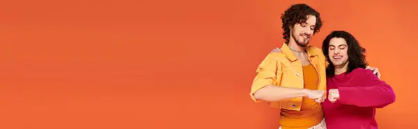 Joyeux jeunes amis gays dans des tenues vives élégantes posant ensemble sur fond orange, fierté, bannière — Photo de stock