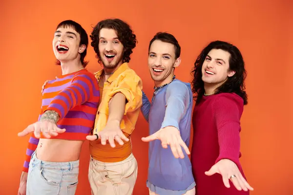 Cheerful young gay men with makeup in vibrant attires posing actively together, pride month — Stock Photo