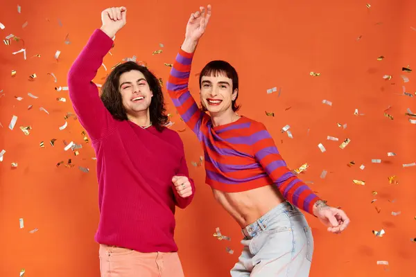 Cheerful good looking gay friends in stylish clothes with makeup posing under confetti rain, pride — Stock Photo
